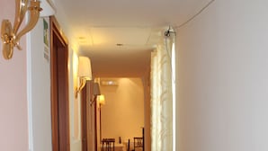 A hallway with a wooden door, a table with chairs, and a curtain. - Aristotele Hotel (Rome)