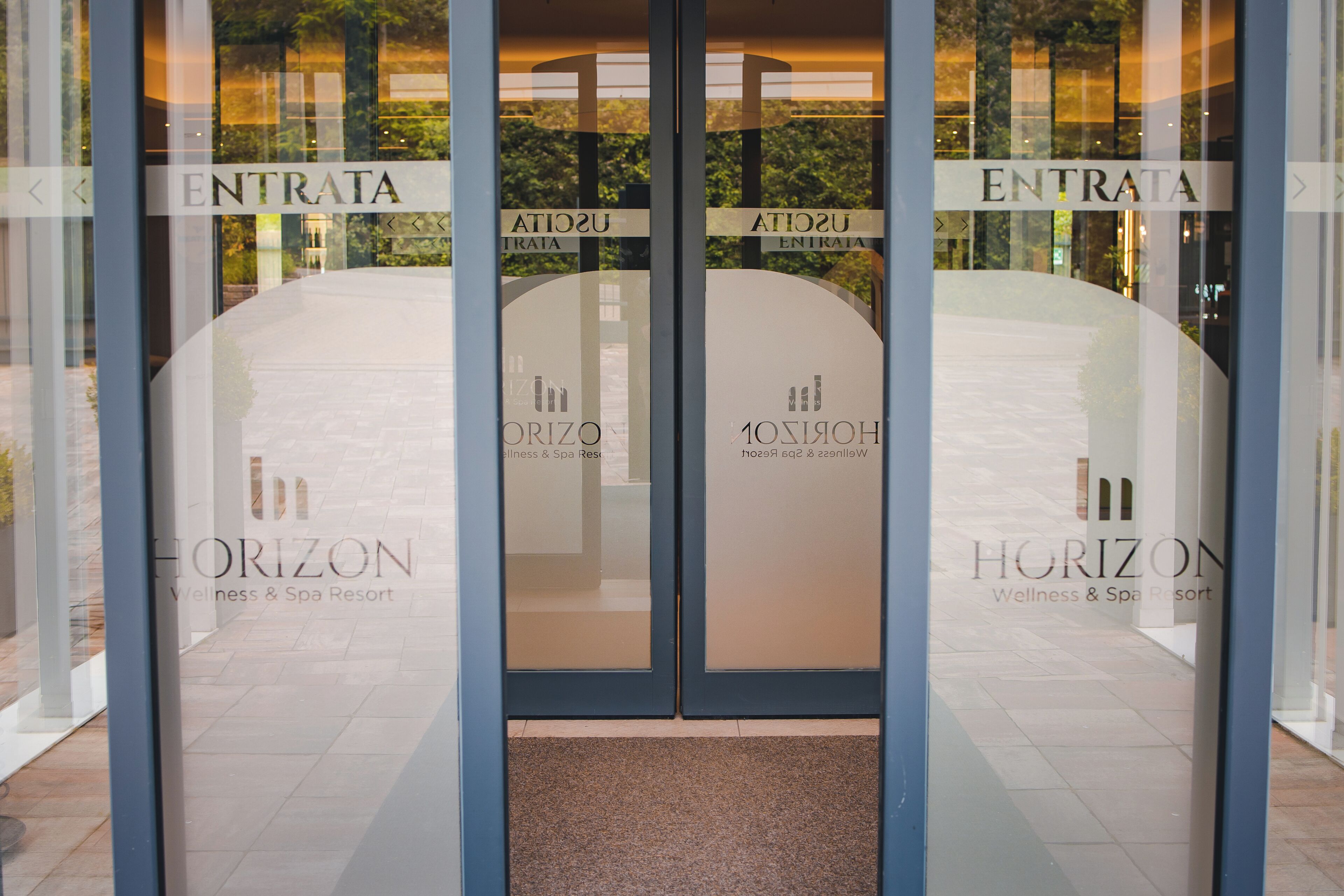 A hotel entrance with glass doors and a sign that reads 'HORIZON Wellness & Spa Resort'.
