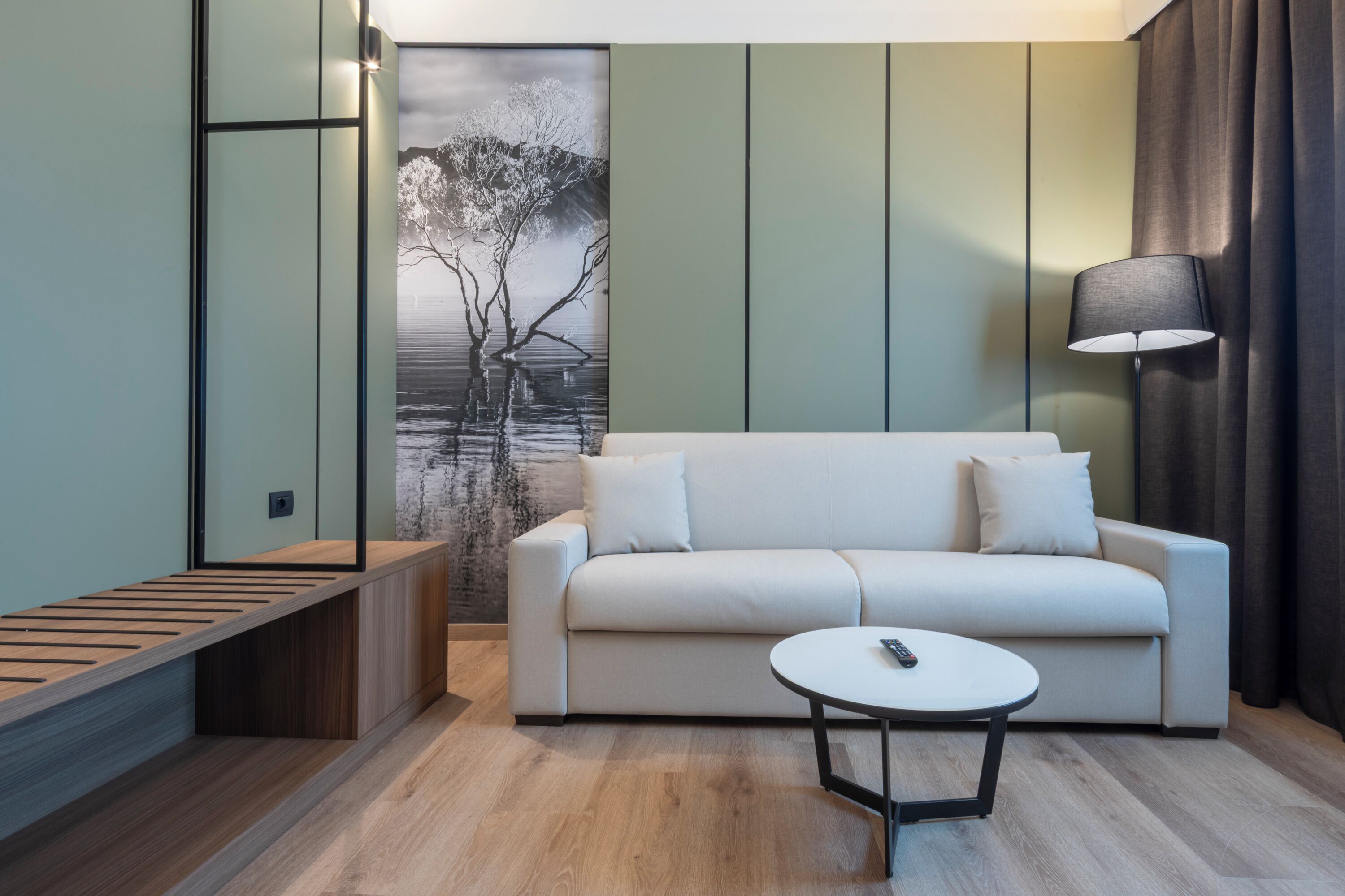Un salon moderne comprenant un canapé, une table basse, un banc et une grande œuvre d’art murale.