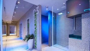 A modern hotel lobby with a reception desk, a large potted plant, and a tiled wall with a mosaic pattern. - Hotel Horizon Wellness & Spa Resort, BW Signature Collection (Varese)