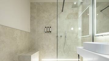 A modern bathroom with a glass-enclosed shower, a white sink, and a large mirror.