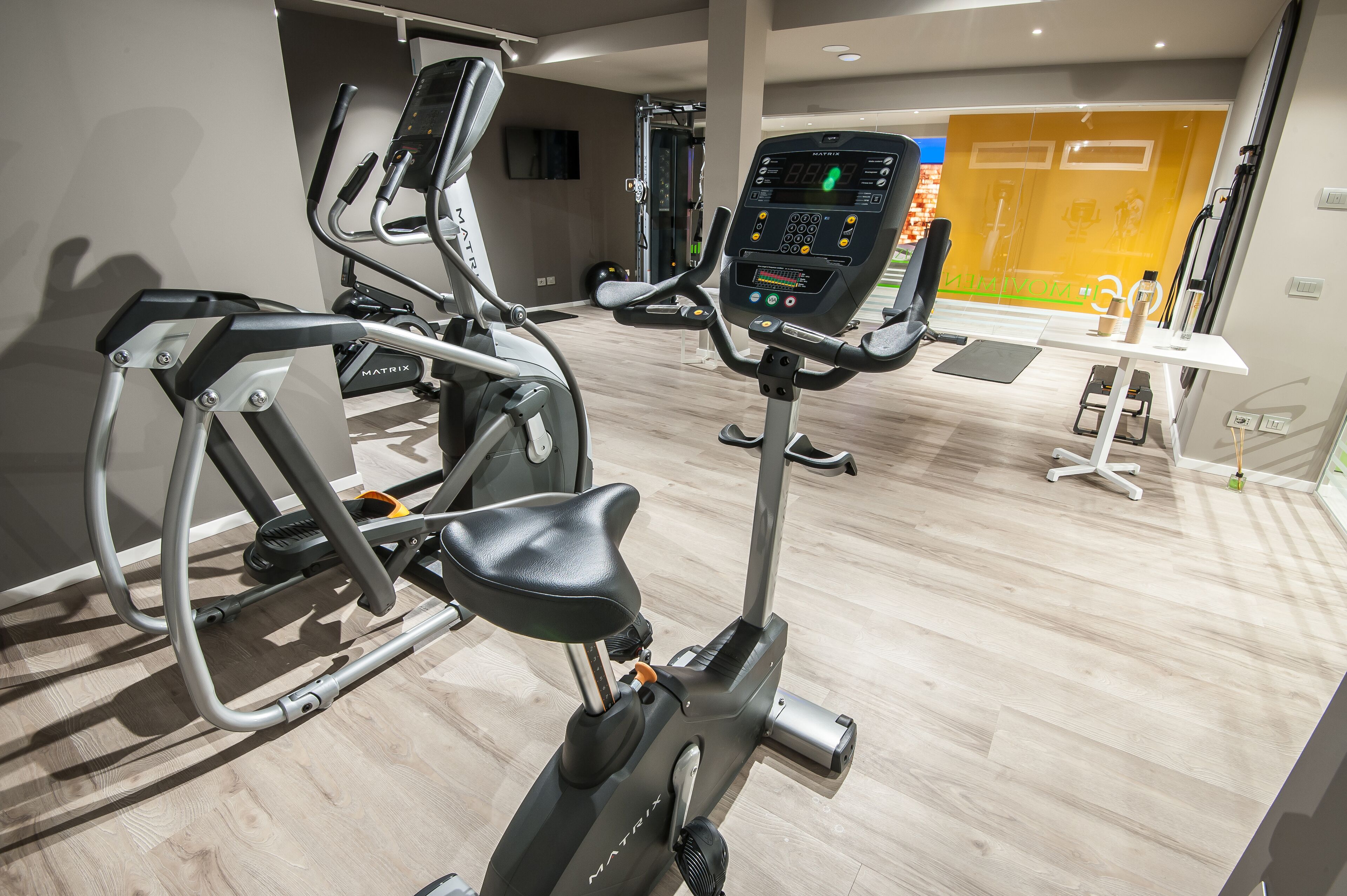 A gym with various exercise equipment including an elliptical and a stationary bike.