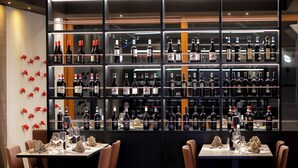 A restaurant with multiple tables, each set with chairs and wine glasses, and a wall of wine bottles behind the tables. - Hotel Horizon Wellness & Spa Resort, BW Signature Collection (Varese)