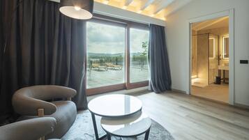 Una habitación moderna con sofá, una mesa redonda y un ventanal con vistas a un balcón y zona exterior.