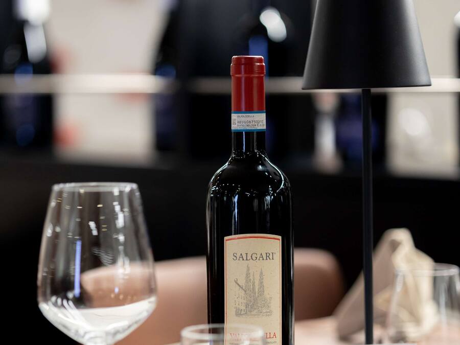 Una mesa de comedor con una botella de vino Salgari, una copa de vino y un letrero que indica una carnicería.