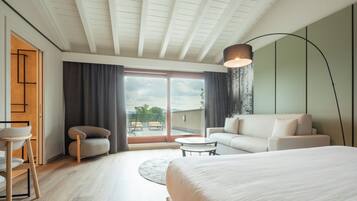 Habitación de hotel moderna con una cama grande, un sofá, una mesita y vistas al exterior.