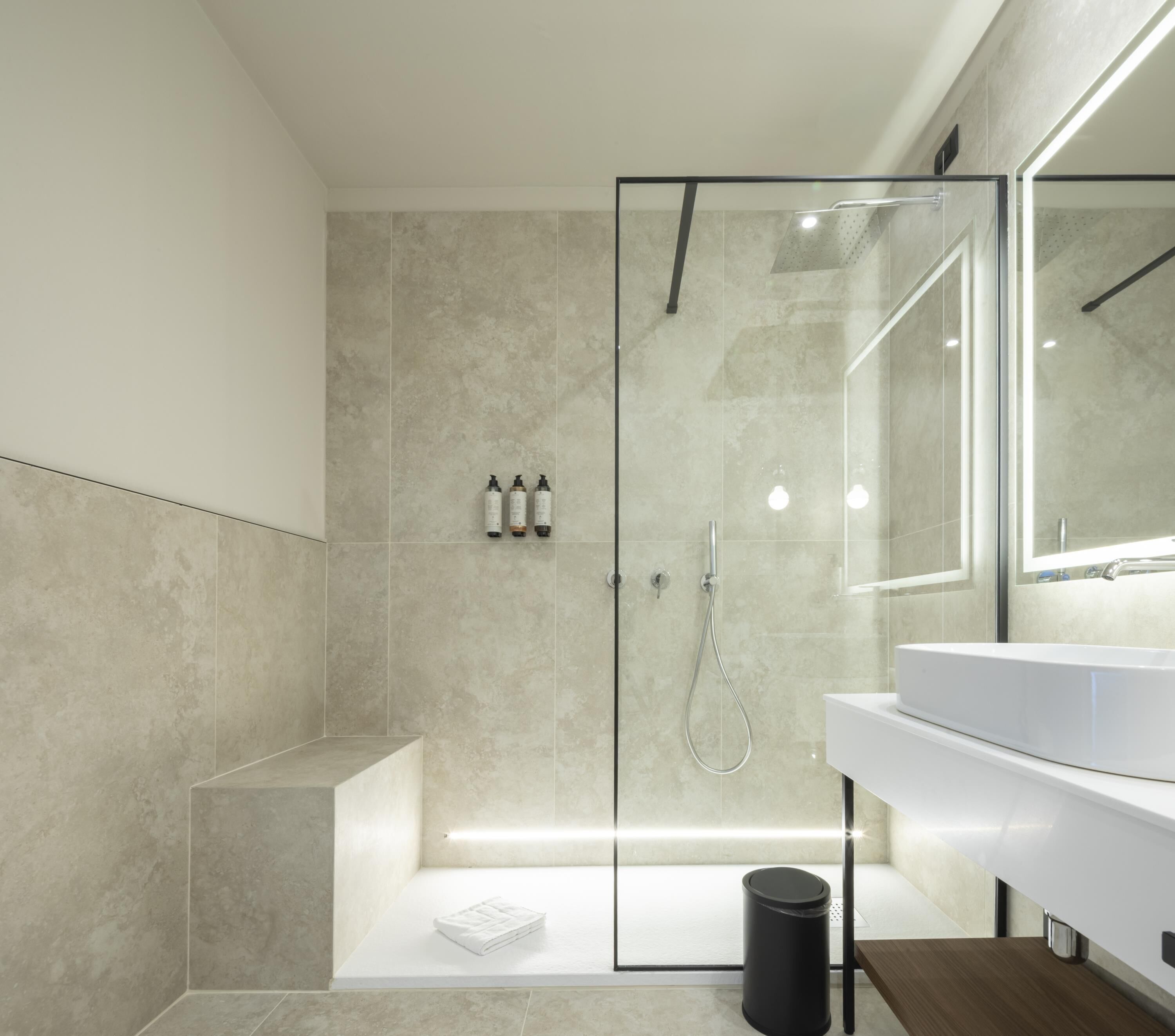 A modern bathroom with a glass-enclosed shower, a white vanity, and a large mirror.