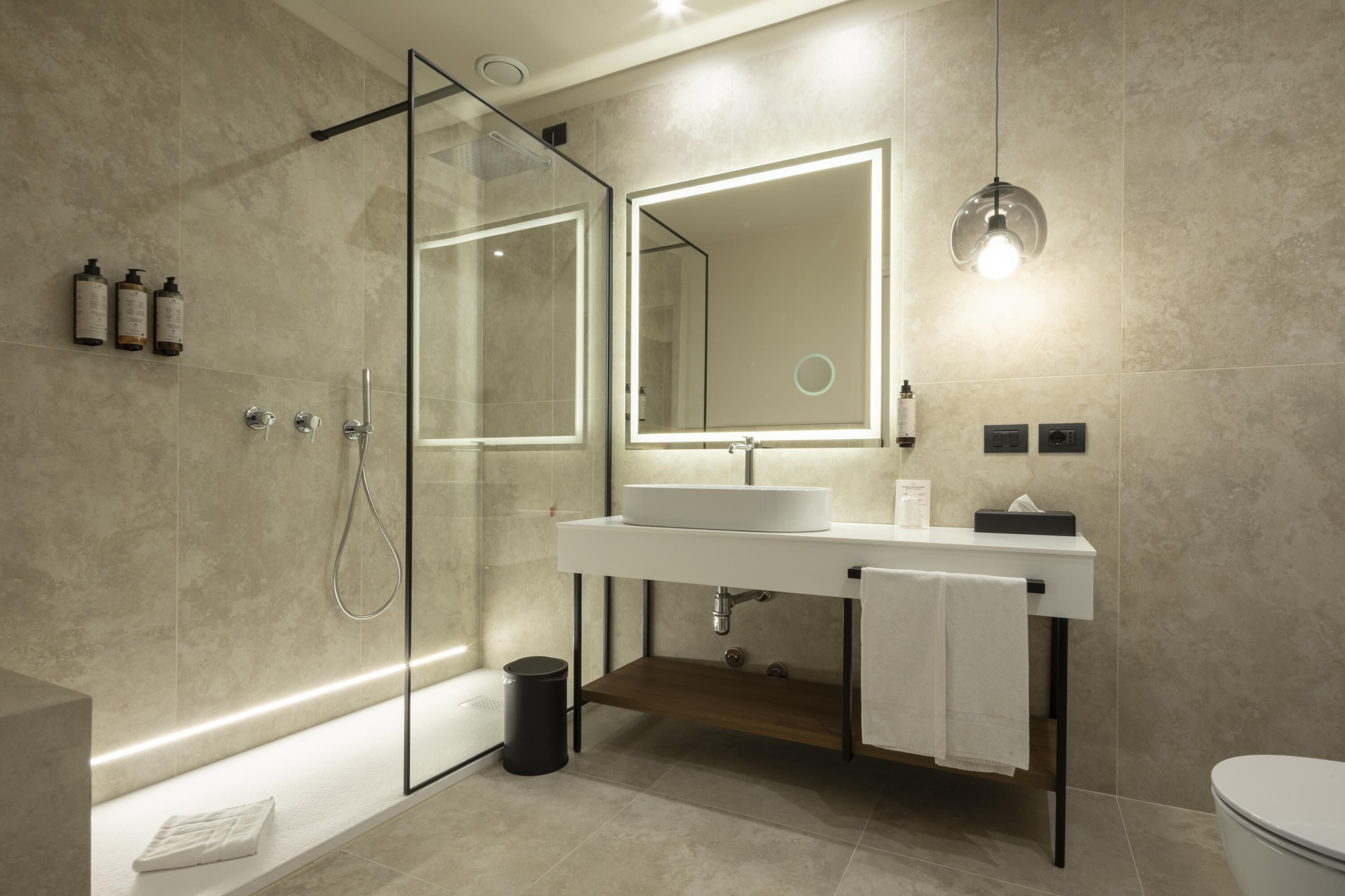 A modern bathroom with a glass shower enclosure, a white sink with a mirror, and a toilet.