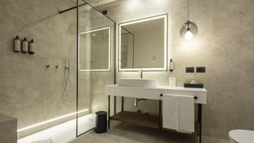 A modern bathroom with a glass shower enclosure, a white sink with a mirror, and a toilet.