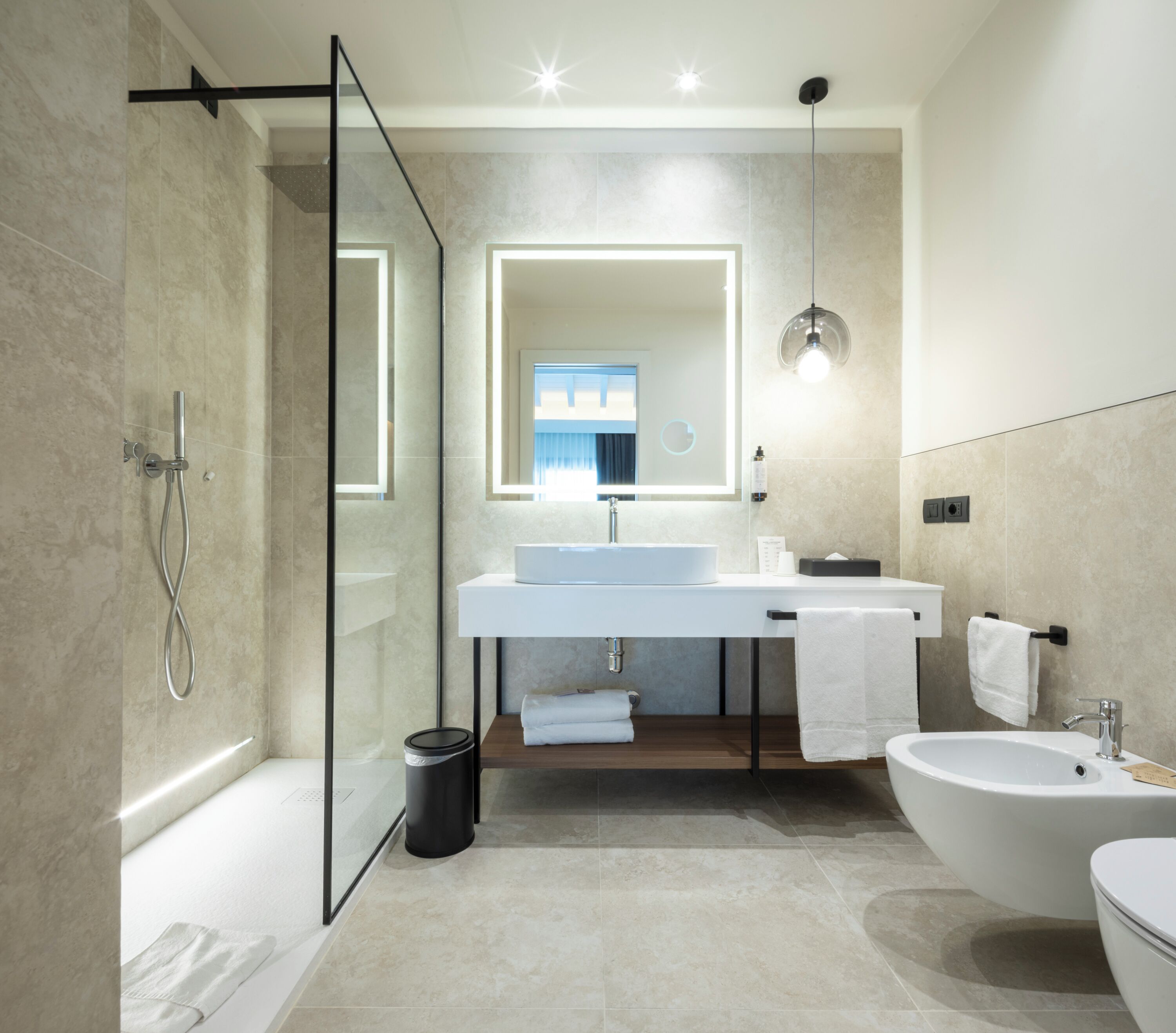 Une salle de bain moderne avec une douche à parois de verre, une baignoire sur pieds, un lavabo avec un miroir et des toilettes.