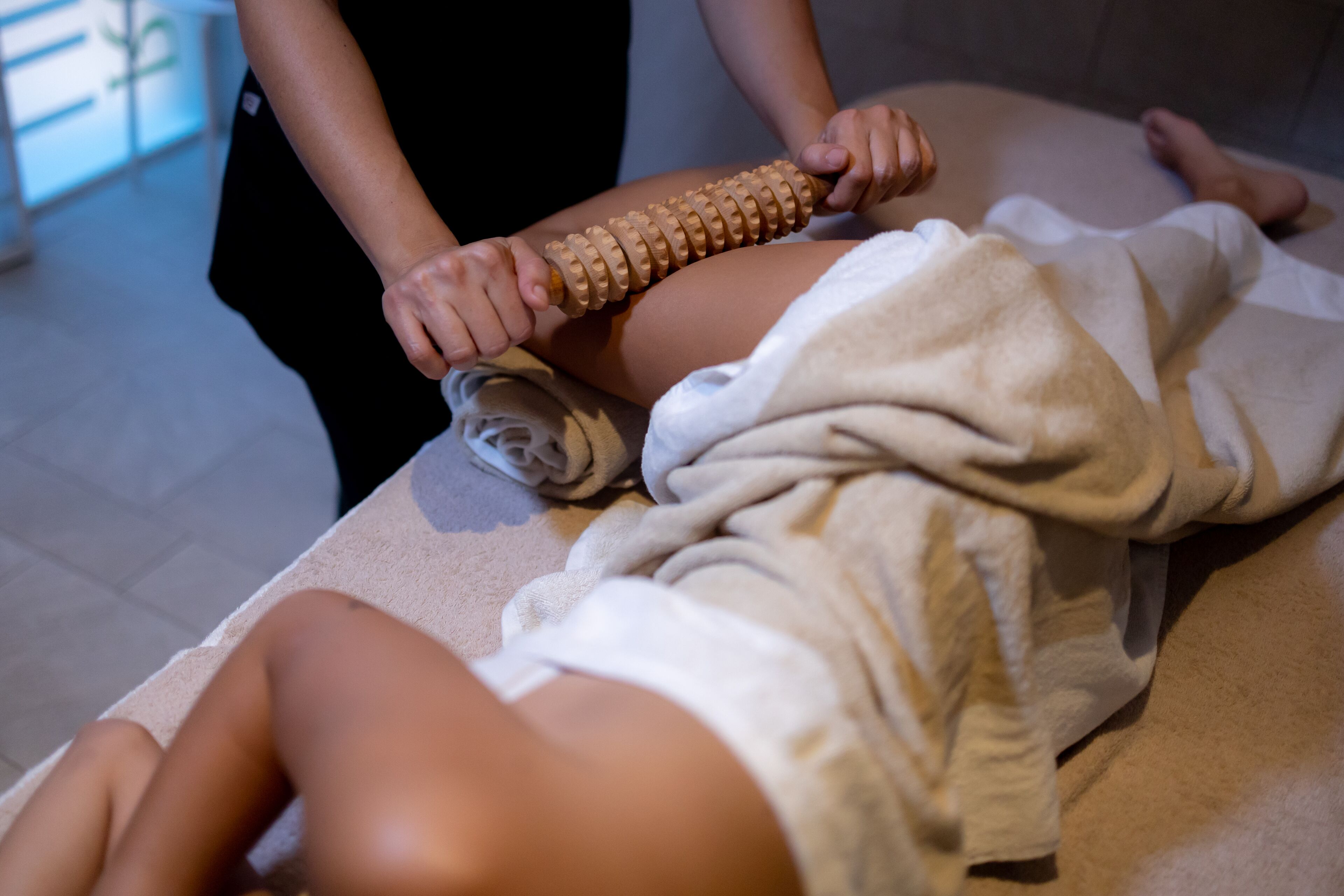 Sesión de masoterapia con un instrumento de madera sobre la pierna de una persona.
