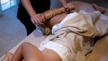 Sesión de masoterapia con un instrumento de madera sobre la pierna de una persona.