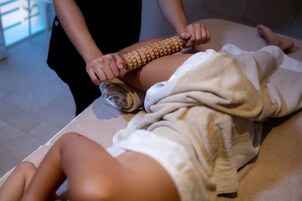Sesión de masoterapia con un instrumento de madera sobre la pierna de una persona.