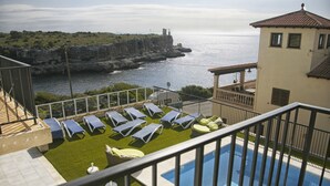 A pool area with sun loungers and a view of the sea. - Hotel Rocamar (Santanyi)
