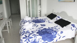 A bedroom with a bed, a desk, and a chair. There is a painting on the wall. - Hotel Rocamar (Santanyi)