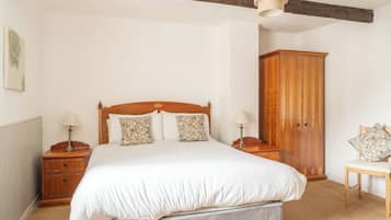A bedroom with a wooden bed, two bedside tables with lamps, a wooden wardrobe, and a chair.