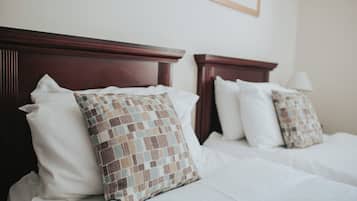 A hotel room with two beds, each with a wooden headboard and white bedding.