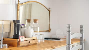 Una encimera de madera con una cafetera, un hervidor, una taza y un recipiente de vidrio.