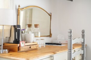 Una encimera de madera con una cafetera, un hervidor, una taza y un recipiente de vidrio.