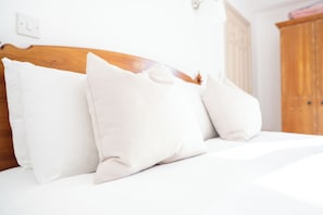 A bed with white bedding and pillows, a wooden headboard, and a white wall with a light switch. - The Lordleaze Hotel And Restaurant (Chard)
