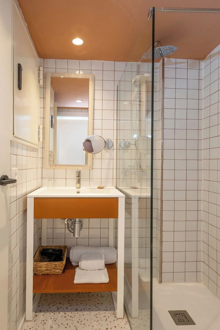 A bathroom with a white sink, mirror, and glass shower enclosure.