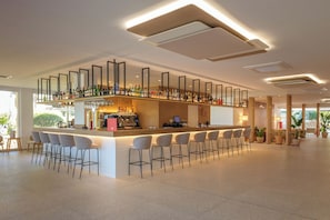 A modern bar area with a high counter, bar stools, and a coffee machine. -  Hotel Cabot Cala Ferrera (Felanitx)