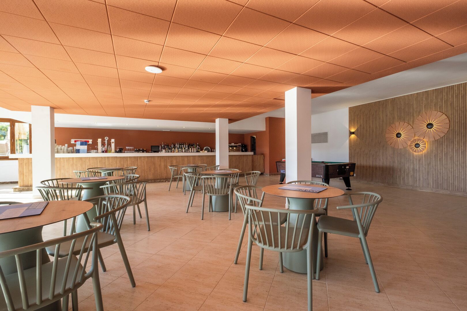 A spacious indoor area with multiple tables and chairs, a bar area, and a pool table.
