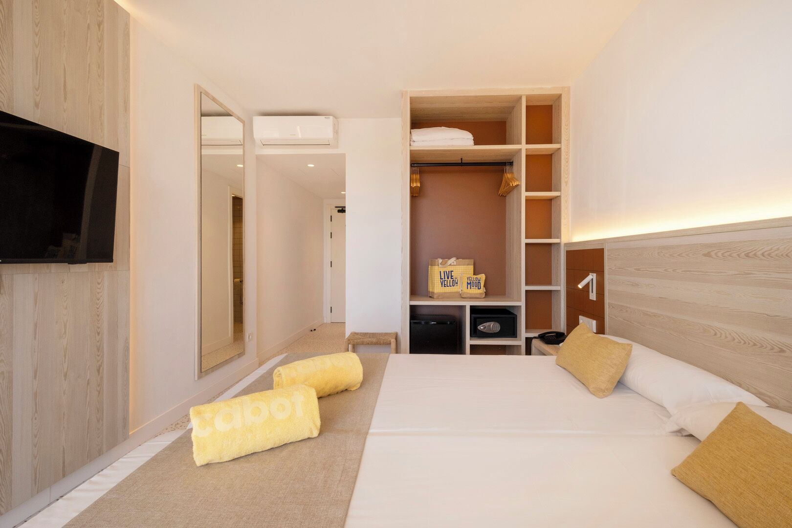 A hotel room with a bed, a television, a wardrobe, and a mirror.