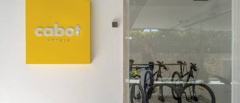 A yellow sign with 'cabot hotels' text, a glass door entrance, and bicycles inside.