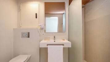 A bathroom with a toilet, a sink with a towel, a mirror, and a shower curtain.