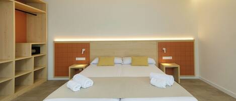 A double bed with white linens, two pillows, and a headboard with a wooden panel design. There are two bedside tables with lamps, and a wooden wardrobe with shelves.