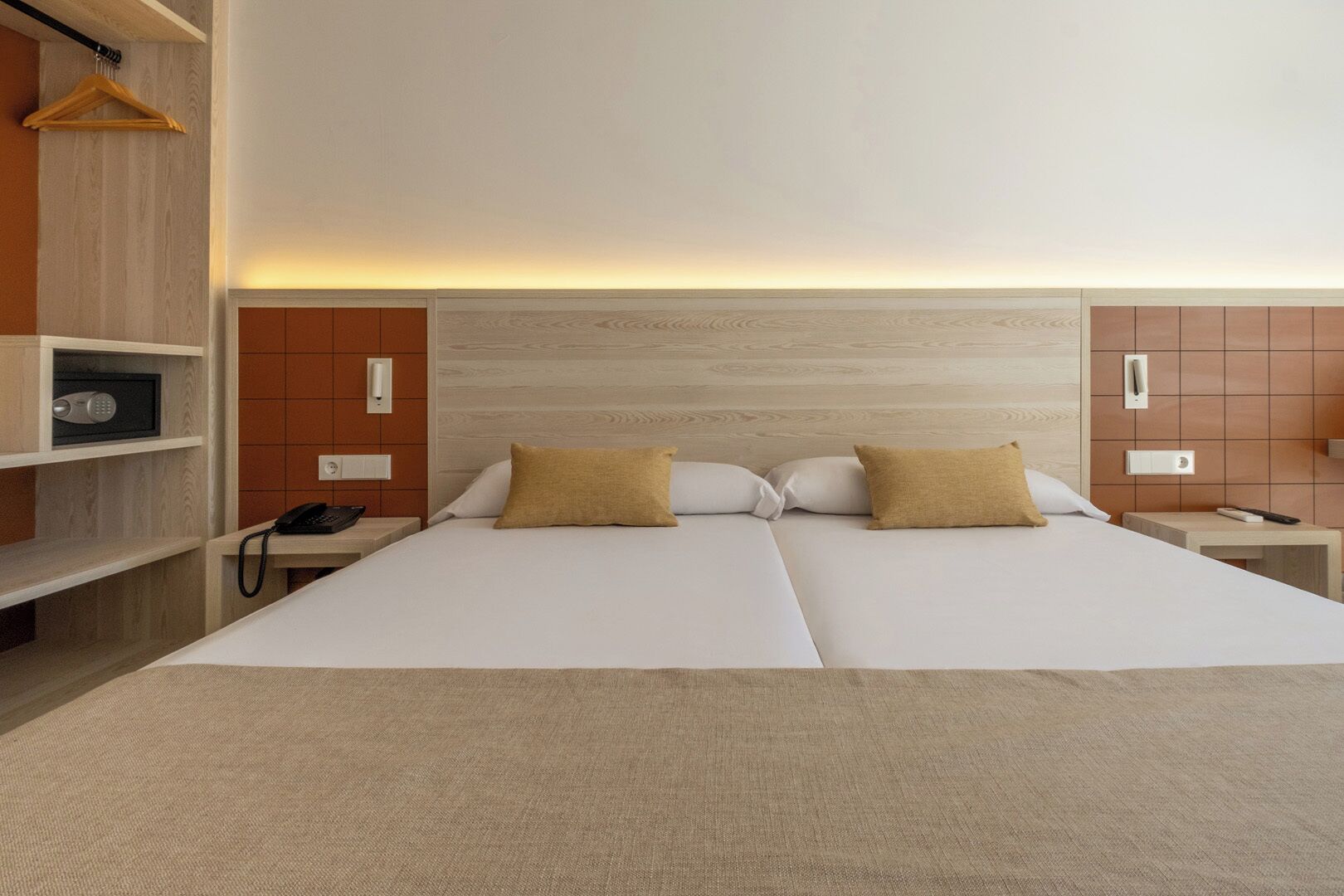 Une chambre d’hôtel avec un grand lit, des tables de chevet, une armoire et un porte-manteau.
