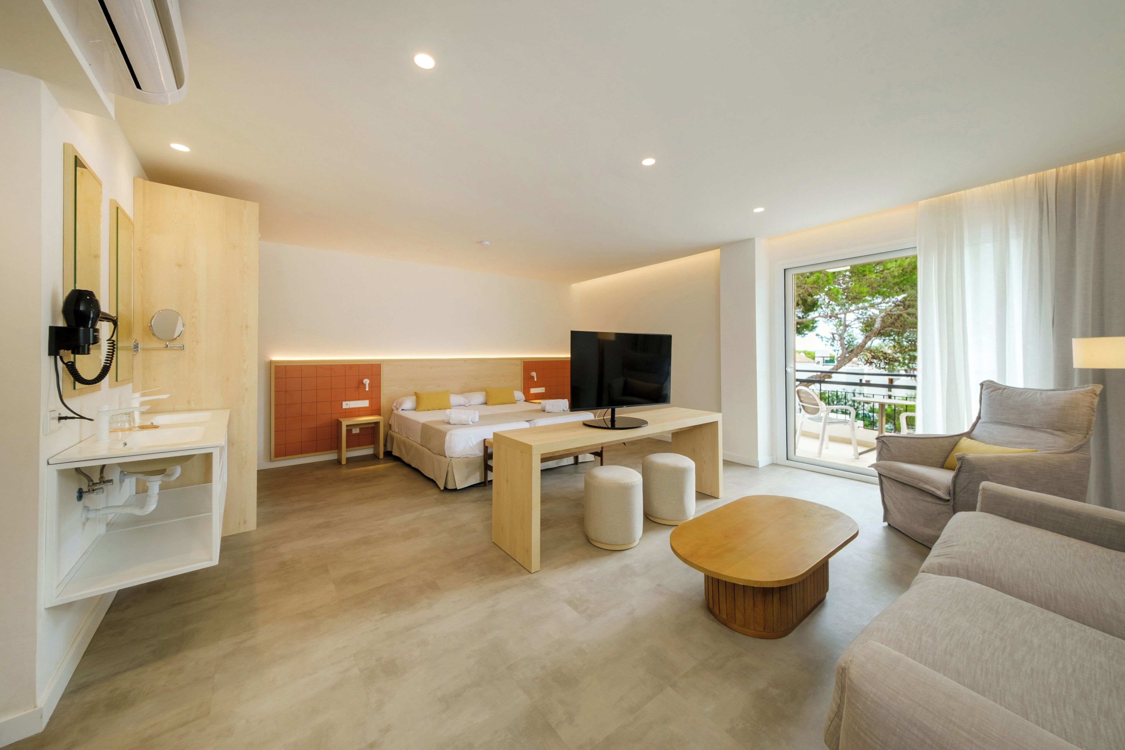 Une chambre d’hôtel moderne équipée d’un lit, d’une télévision, d’une table en bois, d’un canapé et d’une fenêtre donnant sur un beau paysage.