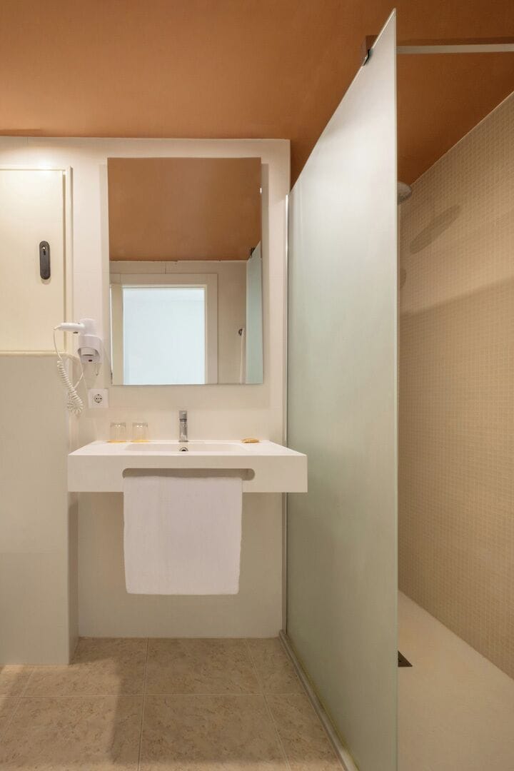 Un baño con un lavamanos blanco, un espejo y una toalla colgada en la pared.