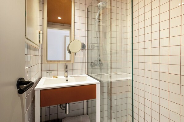A bathroom with a sink, mirror, and shower.