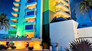 A tall hotel with multiple balconies, a well-lit entrance, and a landscaped garden area. - Hotel Dann Cartagena (Cartagena)