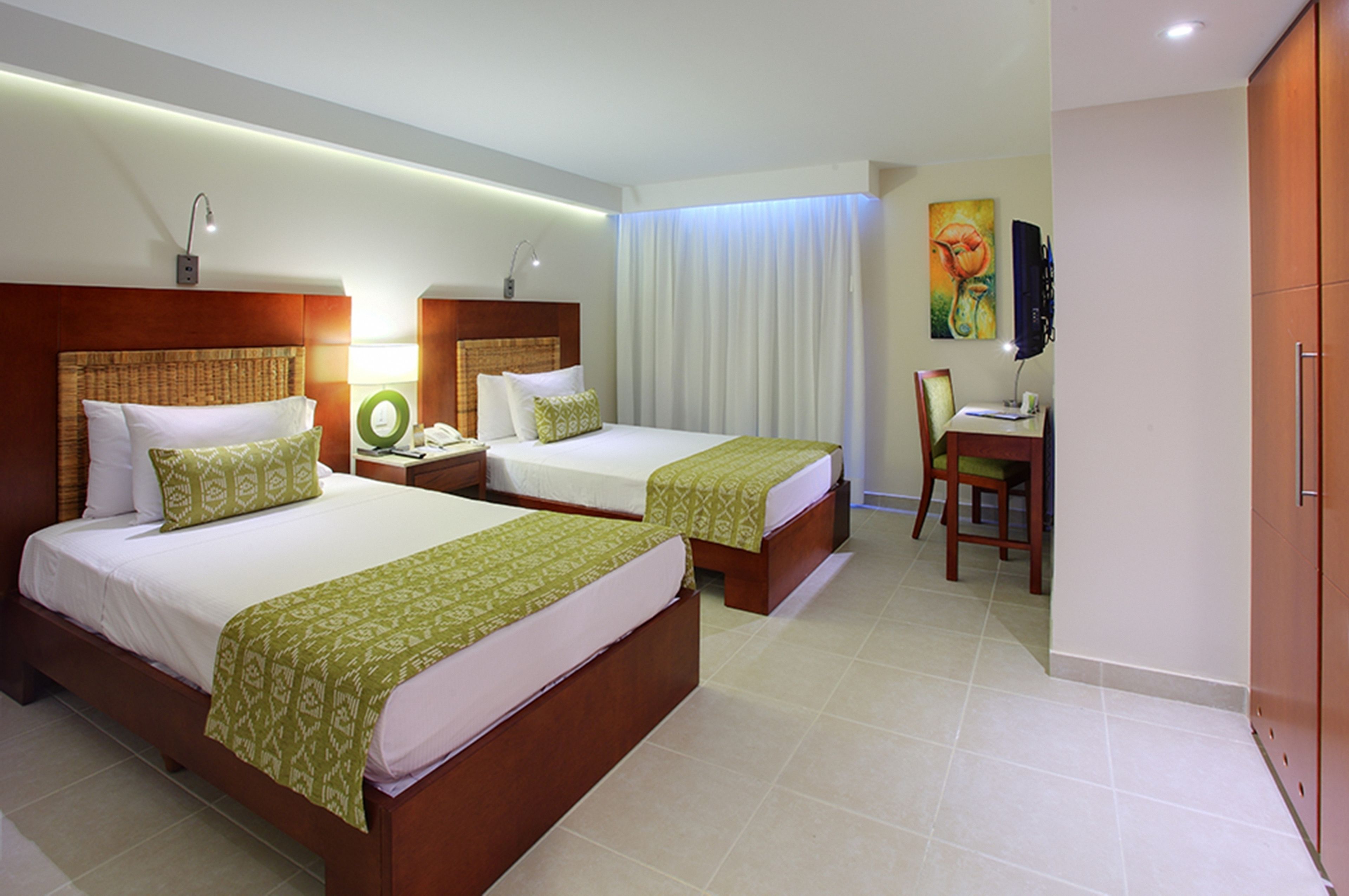 A hotel room with two beds, a desk, a chair, and a wardrobe.
