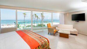 A hotel room with a large bed, a sofa, a TV, and a balcony with a view of the beach and ocean. - Hotel Dann Cartagena (Cartagena)