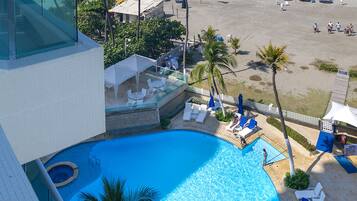 Un hotel con piscina, vistas a la playa y zona de estar al aire libre.