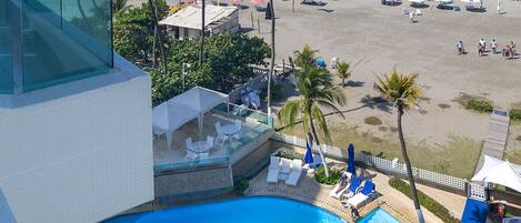 A hotel with a pool, beach view, and outdoor seating area.