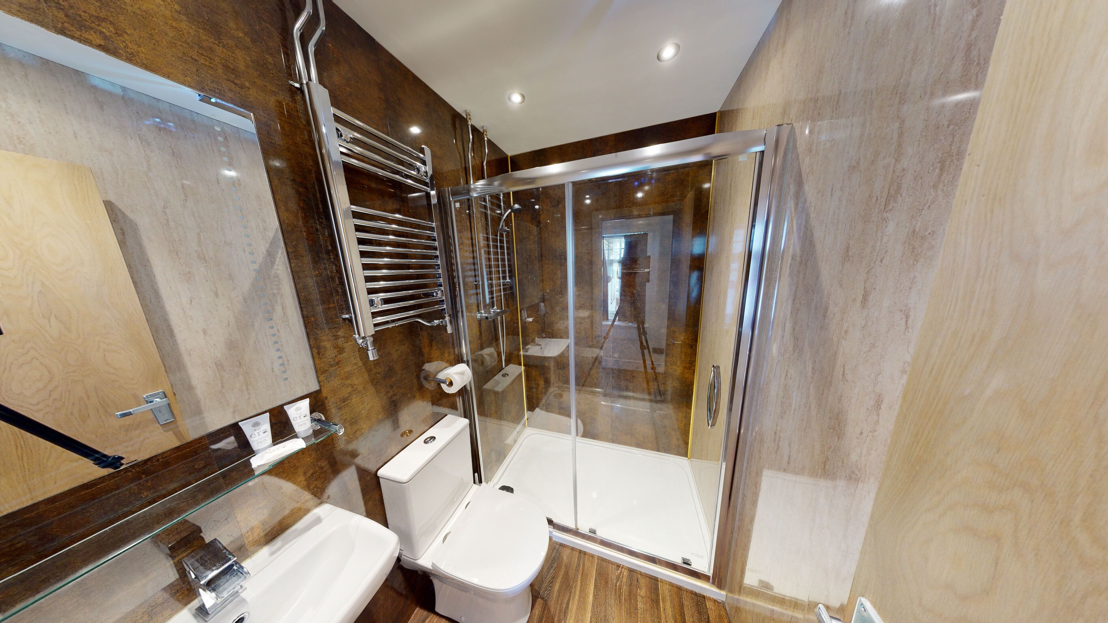Een moderne badkamer met een douchecabine van glas, een toilet en een wastafel.