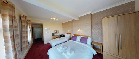 Une chambre d’hôtel avec deux lits, une armoire et une salle de bain visible à travers une porte ouverte.