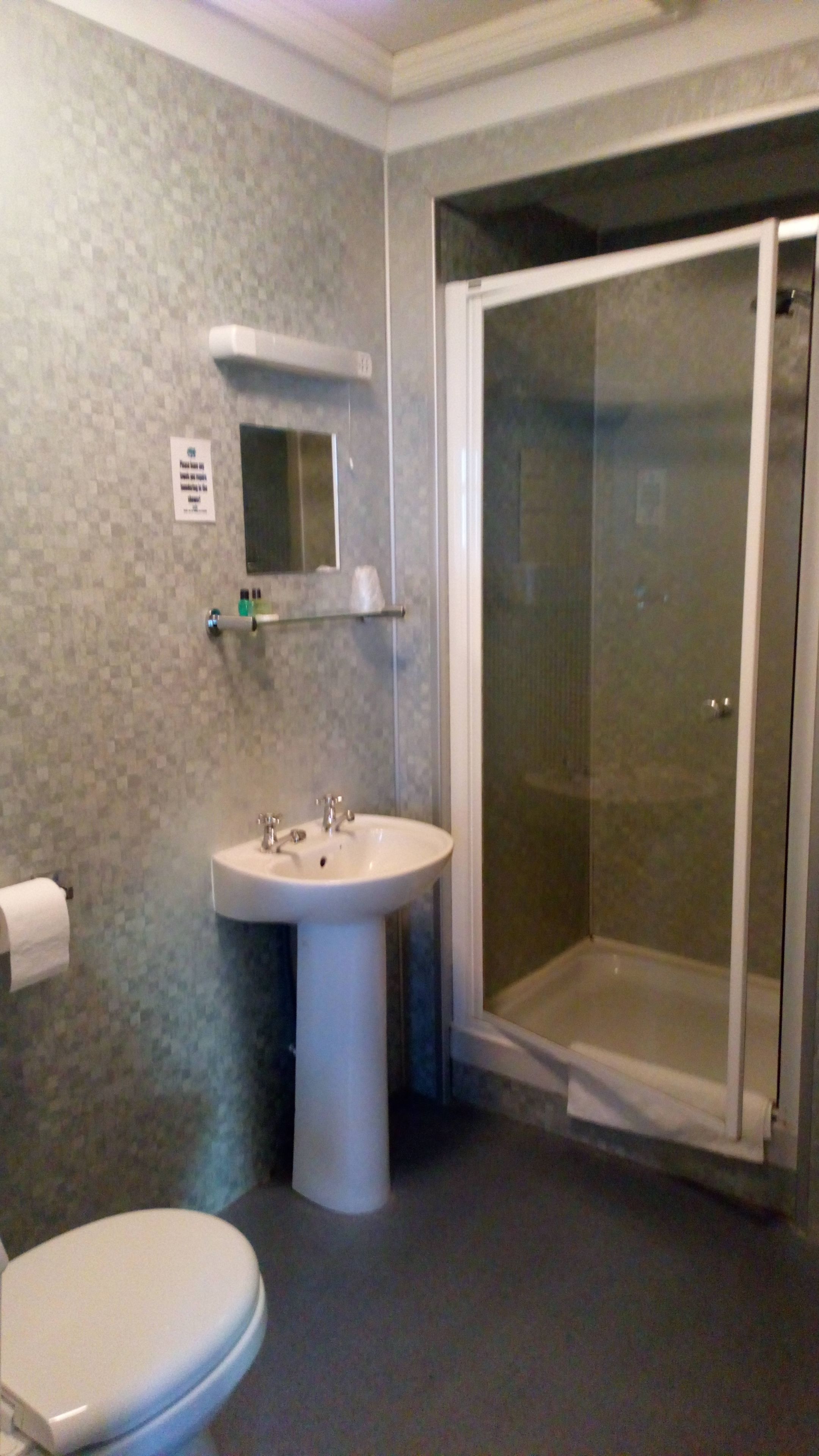 Une salle de bain équipée de toilettes, d’un lavabo et d’une douche à parois de verre.