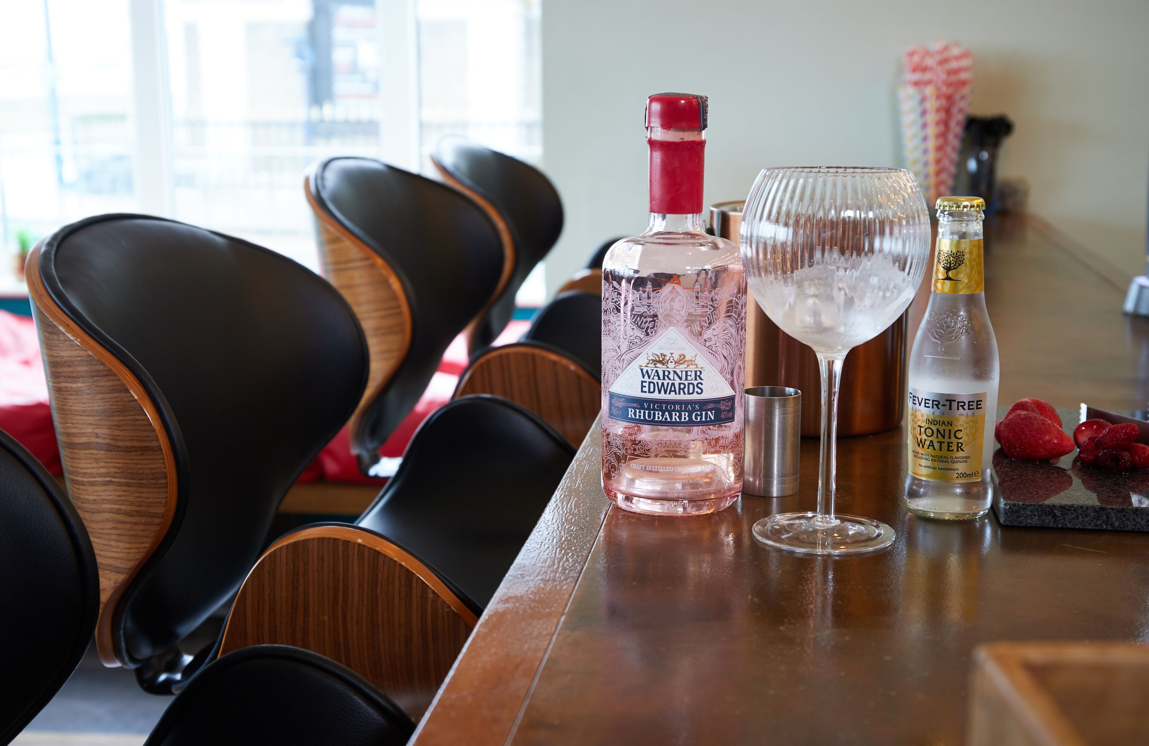 Eine Bar mit einer Flasche Warner Edwards Rhabarber Gin, einem Glas Indian Tonic Water und einer Flasche Fever-Tree.