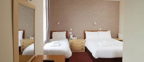 Habitación de hotel con dos camas, un escritorio de madera, un espejo y una alfombra roja.