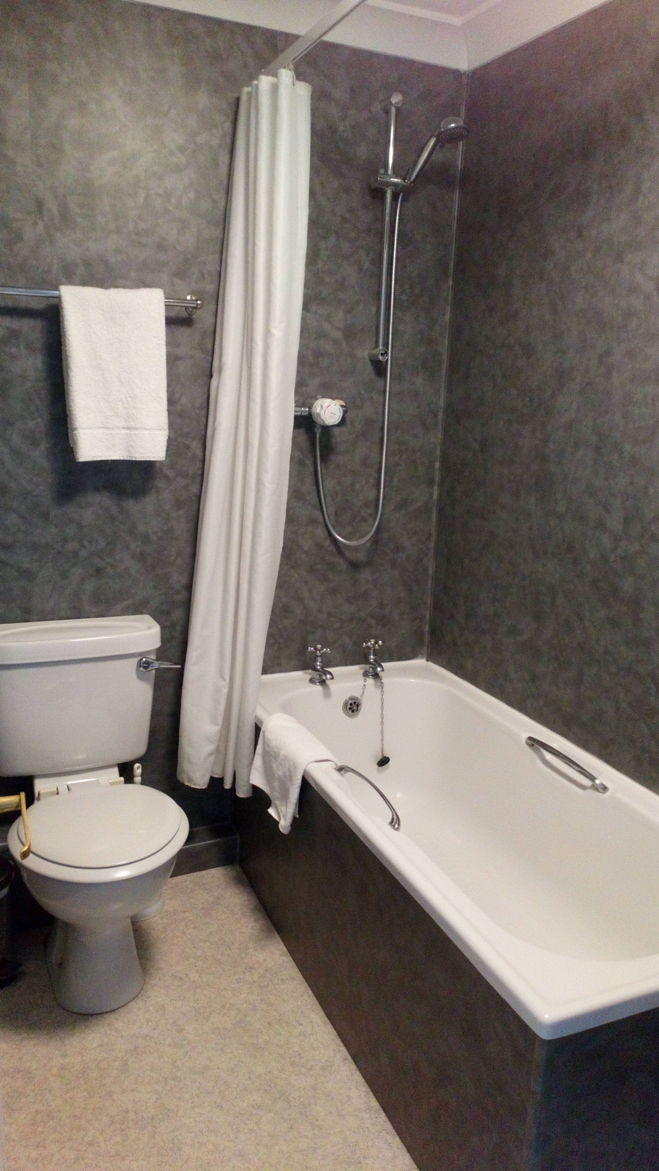 A bathroom with a toilet, bathtub, and shower.