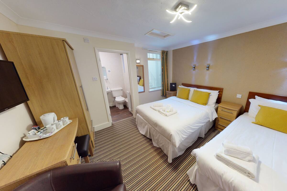Een hotelkamer met twee bedden, een bureau met stoel, een badkamer en een televisie.