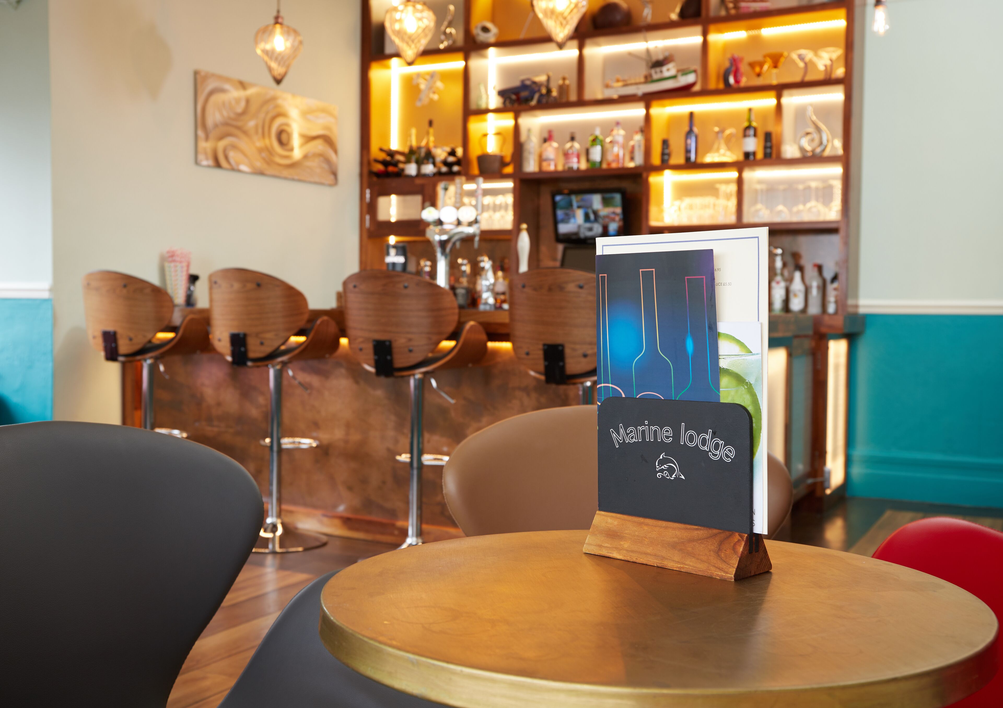 A bar area with wooden chairs, a round table, and a sign reading "Marine Lodge".