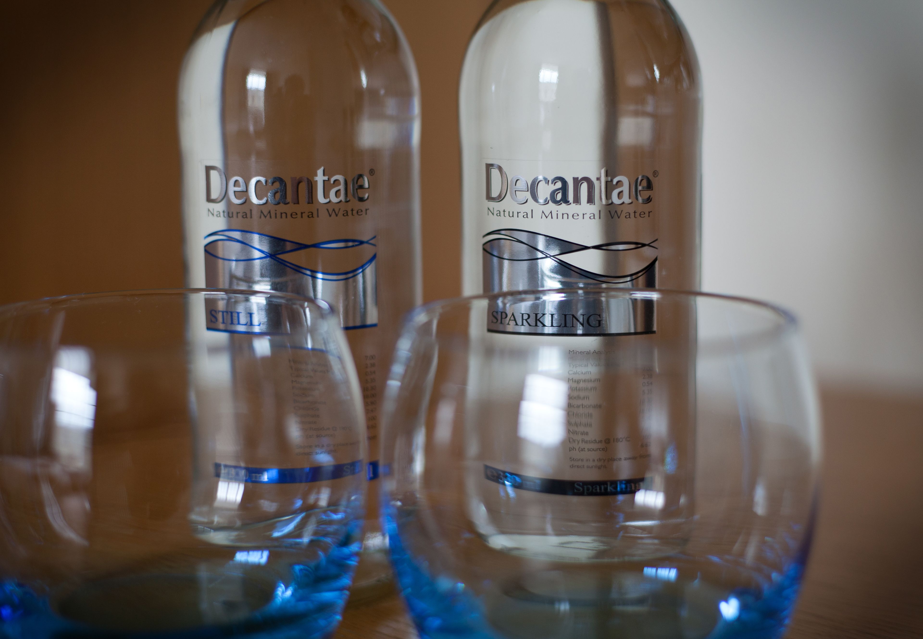 Two bottles of Decantae sparkling mineral water with labels and a blue design element.