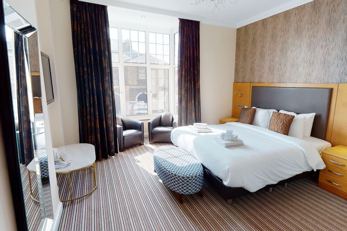 Een hotelkamer met een groot bed, een bureau, een stoel en een klein tafeltje.